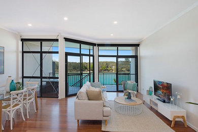 This is an example of a medium sized beach style open plan living room in Gold Coast - Tweed with white walls, dark hardwood flooring and a freestanding tv.