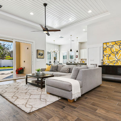 Living room - large modern open concept porcelain tile and brown floor living room idea in Orlando with gray walls, a standard fireplace, a tile fireplace and a wall-mounted tv