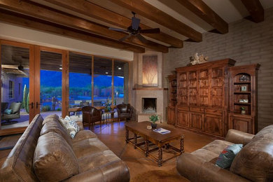 フェニックスにあるラグジュアリーな広いトラディショナルスタイルのおしゃれなLDK (ベージュの壁、コンクリートの床、コーナー設置型暖炉、漆喰の暖炉まわり、内蔵型テレビ) の写真