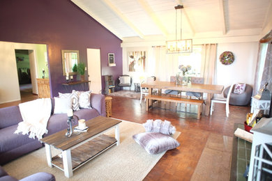 ハワイにあるお手頃価格の広いカントリー風のおしゃれなLDK (紫の壁、無垢フローリング、石材の暖炉まわり、グレーの床) の写真