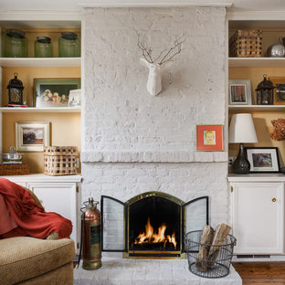 Repräsentatives, Fernseherloses, Abgetrenntes Klassisches Wohnzimmer mit braunem Holzboden, Kaminumrandung aus Backstein, gelber Wandfarbe und Kamin in Kolumbus