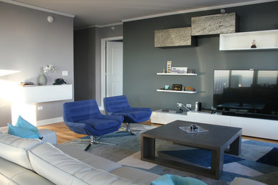 Example of a small trendy open concept medium tone wood floor living room design in Chicago with gray walls, no fireplace and a media wall