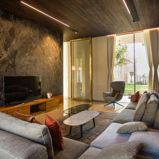 Foto de salón actual con paredes grises, suelo de cemento, televisor independiente y suelo beige