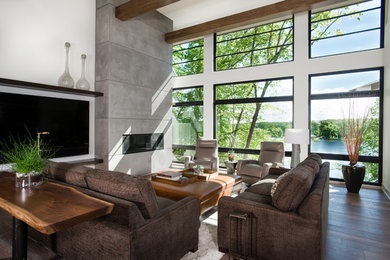 Example of a trendy medium tone wood floor living room design with a standard fireplace and a concrete fireplace