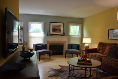Imagen de salón abierto actual de tamaño medio con paredes amarillas, suelo de bambú, todas las chimeneas, marco de chimenea de madera y televisor colgado en la pared