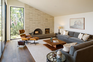Repräsentatives, Fernseherloses, Offenes Modernes Wohnzimmer mit beiger Wandfarbe, dunklem Holzboden, Kamin und Kaminumrandung aus Stein in San Diego