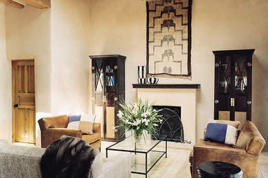 アルバカーキにある広いサンタフェスタイルのおしゃれな応接間 (ベージュの壁、ライムストーンの床、標準型暖炉、木材の暖炉まわり) の写真