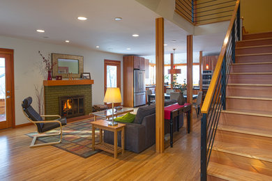 Living room - mid-sized contemporary open concept medium tone wood floor living room idea in Minneapolis with green walls, a standard fireplace, a brick fireplace and no tv