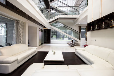 Idée de décoration pour un grand salon design avec un mur blanc et parquet foncé.