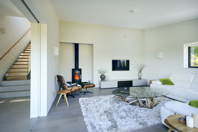 Medium sized contemporary enclosed living room in Surrey with yellow walls, a wood burning stove, a wall mounted tv and grey floors.