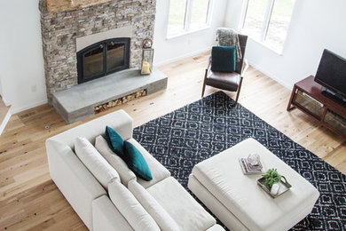 Example of a trendy open concept light wood floor and vaulted ceiling living room design with white walls, a standard fireplace and a stacked stone fireplace