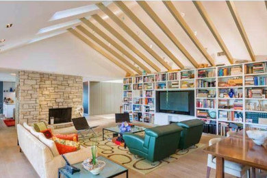 Example of a large trendy open concept light wood floor living room library design in Los Angeles with a stone fireplace, a media wall, a standard fireplace and white walls