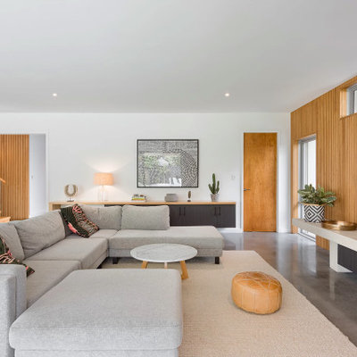 Mid-sized trendy open concept concrete floor and gray floor living room photo in Perth with no fireplace, a wall-mounted tv and white walls