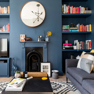 Ispirazione per un soggiorno design di medie dimensioni e chiuso con pareti blu, parquet chiaro, cornice del camino in legno, libreria, camino classico, TV autoportante e pavimento beige