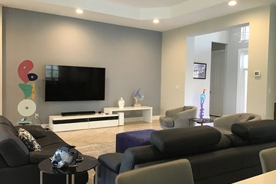 Imagen de salón abierto actual con paredes grises, suelo de baldosas de cerámica, televisor colgado en la pared y suelo beige