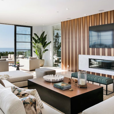 Huge trendy open concept limestone floor and beige floor living room photo with white walls, a wall-mounted tv, a ribbon fireplace and a stone fireplace