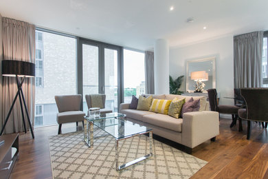 This is an example of a medium sized contemporary open plan living room in London with white walls, a freestanding tv and dark hardwood flooring.
