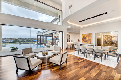 Example of a huge trendy open concept medium tone wood floor and brown floor living room design in Orange County with white walls
