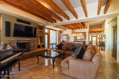 Example of a large southwest open concept limestone floor and beige floor living room design in Phoenix with multicolored walls, a standard fireplace, a stone fireplace and a wall-mounted tv