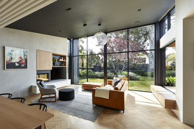 Aménagement d'un salon contemporain ouvert avec une salle de réception, un mur gris, parquet clair, une cheminée standard, un manteau de cheminée en plâtre et un téléviseur indépendant.