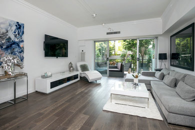Esempio di un soggiorno minimal di medie dimensioni e aperto con pareti bianche, parquet scuro, TV a parete e pavimento grigio