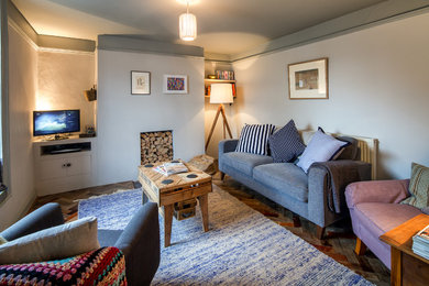 Kleines, Abgetrenntes Modernes Wohnzimmer mit blauer Wandfarbe und gebeiztem Holzboden in Devon