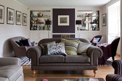 Mittelgroßes, Fernseherloses, Abgetrenntes Country Wohnzimmer mit Hausbar, beiger Wandfarbe, braunem Holzboden, Kamin und verputzter Kaminumrandung in London