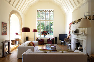 Imagen de salón para visitas contemporáneo grande con paredes beige, suelo de madera en tonos medios, todas las chimeneas y televisor independiente