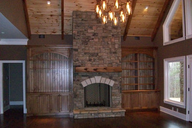 Foto de salón para visitas cerrado de estilo americano grande sin televisor con paredes beige, suelo de madera oscura, todas las chimeneas y marco de chimenea de piedra