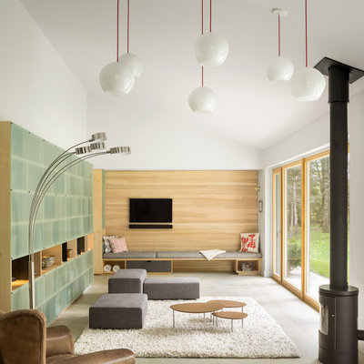 Example of a mid-sized trendy concrete floor living room design in Portland Maine with white walls, a wood stove and a wall-mounted tv