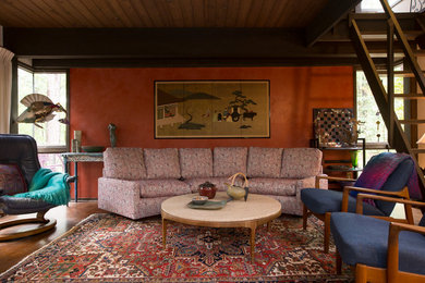 Example of a mid-sized eclectic open concept medium tone wood floor and orange floor living room library design in Raleigh with red walls and no tv