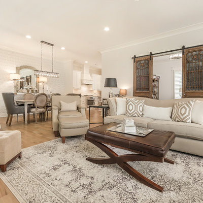 Example of a mid-sized country open concept light wood floor and beige floor living room design in Birmingham with white walls, a standard fireplace, a stone fireplace and a wall-mounted tv