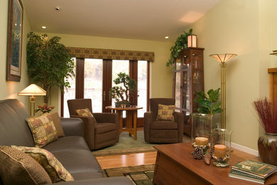 Diseño de salón de estilo americano de tamaño medio sin televisor con paredes verdes, suelo de madera clara, chimenea de doble cara y marco de chimenea de madera