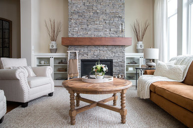 Example of a mid-sized transitional formal and open concept medium tone wood floor and brown floor living room design in Calgary with beige walls, a standard fireplace, a stone fireplace and no tv