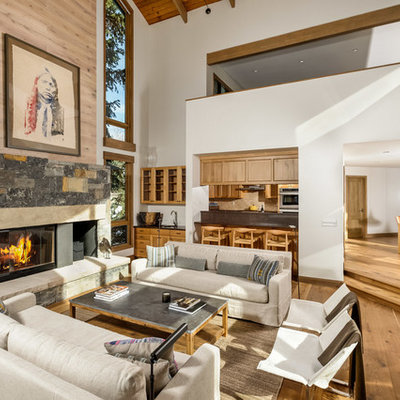 Inspiration for a mid-sized rustic formal and open concept medium tone wood floor living room remodel in Denver with white walls, a standard fireplace, a stone fireplace and no tv