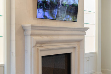 Modelo de salón clásico renovado grande con suelo de madera oscura, todas las chimeneas, marco de chimenea de piedra, televisor colgado en la pared y suelo marrón