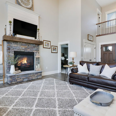 Large country formal and open concept medium tone wood floor and brown floor living room photo in Grand Rapids with gray walls, a standard fireplace, a stone fireplace and a wall-mounted tv