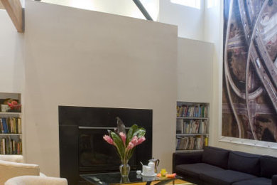 Foto de salón tipo loft moderno extra grande con paredes blancas, suelo de madera clara y marco de chimenea de piedra