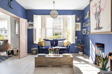 Imagen de salón cerrado bohemio de tamaño medio sin chimenea con paredes azules, suelo de madera clara y suelo gris