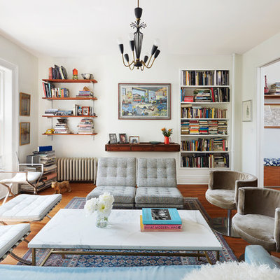 Example of an eclectic enclosed medium tone wood floor living room library design in New York with white walls