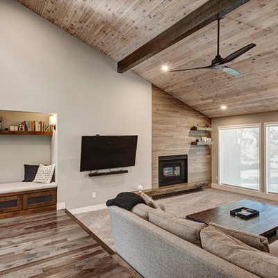 Inspiration for a large 1950s open concept carpeted, beige floor and vaulted ceiling living room remodel in Denver with beige walls, a standard fireplace, a wood fireplace surround and a wall-mounted tv