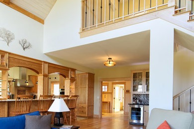 Großes, Offenes Uriges Wohnzimmer mit weißer Wandfarbe, hellem Holzboden, Kamin, Kaminumrandung aus Stein, Multimediawand und braunem Boden in Portland Maine