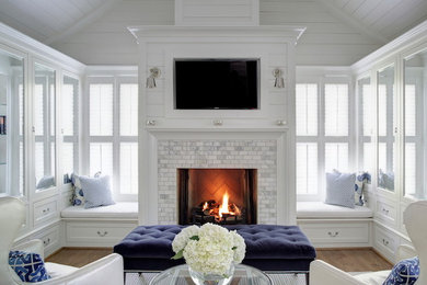 This is an example of a medium sized traditional open plan living room in Calgary with white walls, medium hardwood flooring, a standard fireplace, a tiled fireplace surround, a wall mounted tv and brown floors.