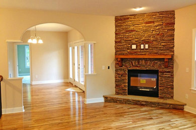 Imagen de salón abierto tradicional grande sin televisor con paredes beige, suelo de madera clara, todas las chimeneas y marco de chimenea de ladrillo