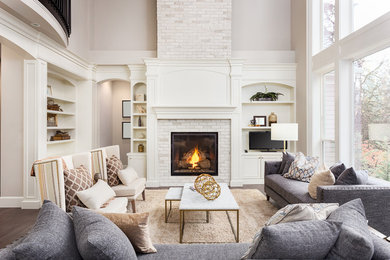 Large classic formal enclosed living room in Toronto with beige walls, dark hardwood flooring, a standard fireplace, a brick fireplace surround, a freestanding tv, brown floors and feature lighting.