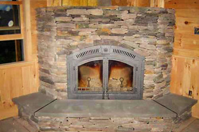 Example of a living room design in Burlington with brown walls, a standard fireplace and a stone fireplace