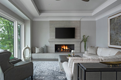 Photo of a large traditional formal enclosed living room in Detroit with grey walls, medium hardwood flooring, a standard fireplace, a stone fireplace surround, a wall mounted tv and grey floors.