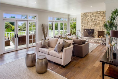 Example of a large transitional medium tone wood floor living room design in Other with beige walls, a standard fireplace and a stone fireplace