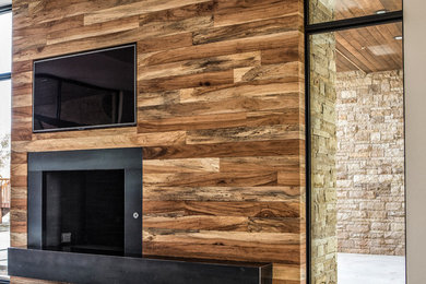 Großes, Offenes Modernes Wohnzimmer mit bunten Wänden, braunem Holzboden, Kamin, Kaminumrandung aus Holz und TV-Wand in Austin