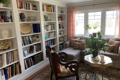 Modelo de biblioteca en casa cerrada clásica renovada de tamaño medio con paredes beige y suelo de madera en tonos medios